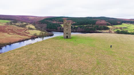 Old-derelict-castle,-monument,-disused-stone-tower,-with-people-walking-around-and-flying-a-drone