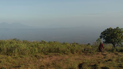 A-young-tribal-African-boy-walks-accross-a-mountain-landscape-in-Uganda