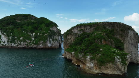 Aerial-tracking-shot-of-a-tour-boat-and-the-Mismaloya-arches,-in-Mexico