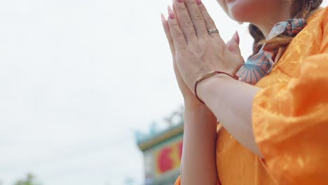 Close-up-hands-of-an-Asian-girl-in-national-costume-parying-at-a-pagoda