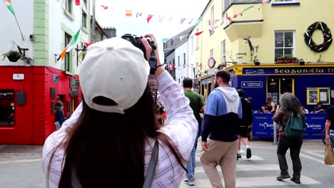 Mujer-Turista-Tomando-Fotografías-En-La-Concurrida-Calle-Quay,-Galway