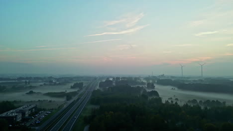 Atmospheric-Landscape-Of-Roads-On-A-Misty-Morning-With-Wind-Turbines-In-The-Background