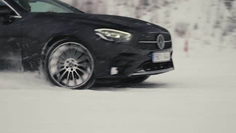 Black-car-drive-on-snowy-road-during-blizzard,-winter-outdoor-drift-event