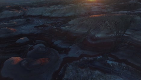 Circling-over-Bentonite-Hills-landscape-in-Utah-at-sunset,-USA