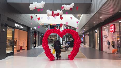 Father-and-little-child-walk-through-a-heart-shaped-balloon-arch-in-a-mall