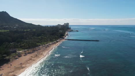 Slow-aerial-flying-backwards-of-Waikiki-Beach-on-sunny-day,-Honolulu,-Hawaii,-USA