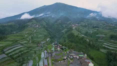 Reveal-drone-shot-of-"Negeri-Kahyangan"-outdoor-park-with-Mount-Merbabu-on-the-background-in-clear-weather