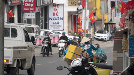 Frau-Mit-Traditionellem-Vietnamesischen-Hut-Trägt-Müll-Auf-Einer-Bambusstange-Auf-Der-Schulter,-Balanciert-Aus-Und-Läuft-Den-Straßenverkehr-In-Der-Innenstadt-Von-Da-Lat-Entlang---Teleaufnahme-Zur-Verfolgung