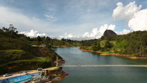 Aerial-view-rising-away-from-people-on-a-bridge-at-the-Peñol-Guatapé-Reservoir-in-Colombia