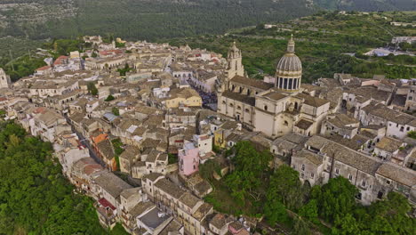 Ragusa-Italy-Aerial-v4-birds-eye-view-reverse-flyover-Ibla-town-center-capturing-charming-townscape,-Cathedral-of-San-Giorgio,-hilly-terrain-and-verdant-valleys---Shot-with-Mavic-3-Cine---June-2023