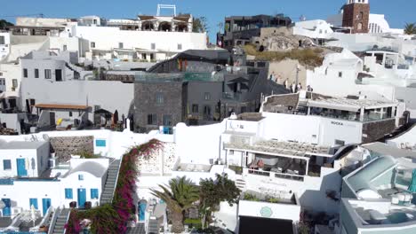 Traveling-Couple-Waving-and-Operating-a-Drone-Revealing-Imerovigli-Village,-Santorini