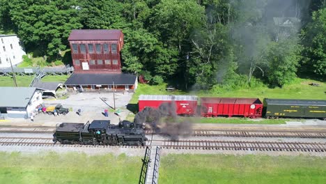 Luftaufnahme-Einer-Antiken-Dampflokomotive,-Die-An-Einem-Sonnigen-Sommermorgen-Langsam-Rückwärts-Fährt,-Um-Sich-Einem-Bahnhof-Zu-Nähern