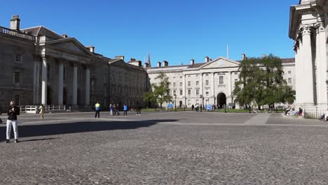 Tourists-and-students-explore-Trinity-College-front-square-and-Regent-House-exterior,-Dublin