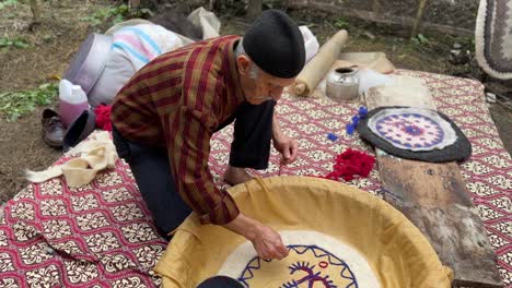 old-artist-man-design-colorful-woolen-fibers-to-make-traditional-persian-rug-namad-felt-beating-process-made-carpet-sheep-wool-material-to-use-covering-floor-in-cold-season-traditional-iran-skill