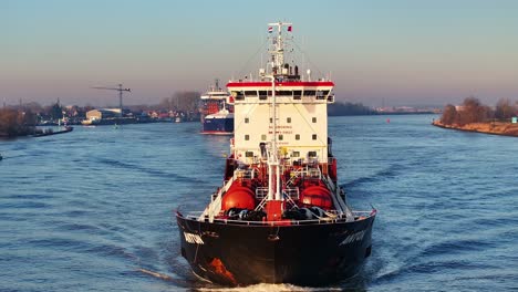 Close-up-panning-view-of-a-fully-loaded-tanker-navigating-on-a-river-during-sunrise