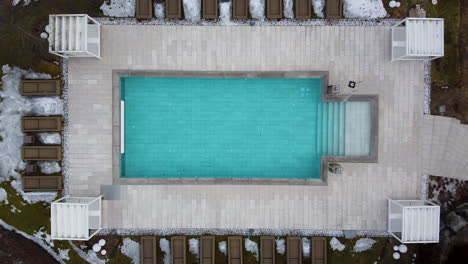 A-heated-pool-in-an-alpine-luxury-resort-turns-more-blue-as-the-drone-departs-straight-up