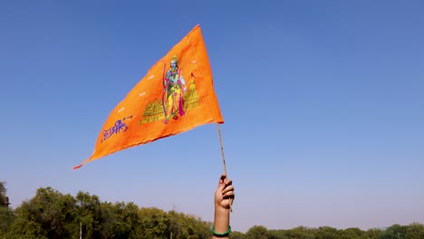 Heilige-Safran-Flagge-Mit-Lord-Rama-Idol-In-Der-Hand-Mit-Strahlend-Blauem-Himmelshintergrund-Am-Tag