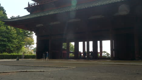 Turistas-Explorando-Koyasan-Daimon,-Una-Gran-Puerta-Histórica-En-Un-Entorno-Boscoso-Sereno,-En-Un-Día-Claro