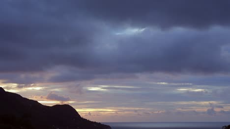 Sunset-time-lapse-on-mountain-view-at-beau-vallon,-golden-colour-in-the-sky-with-moving-clouds,-Mahe,-Seychelles,-25-fps
