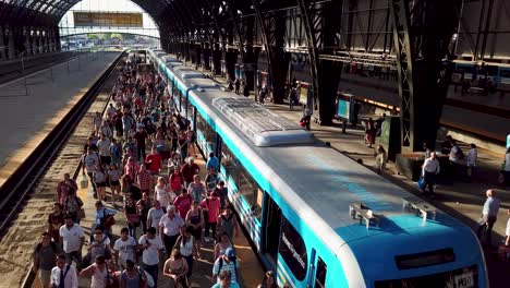 Busy-train-station-with-a-crowd-of-commuters-leaving-a-Trenes-Argentinos-train,-daylight