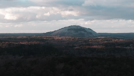 Imágenes-Aéreas-De-Drones-De-La-Montaña-De-Piedra-En-El-Parque-Stone-Mountain,-Georgia,-Que-Muestran-La-Majestuosa-Montaña-Con-Exuberantes-árboles-Verdes-Y-Nubes-Flotantes