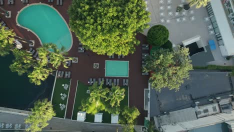 Top-down-view-of-a-hotel-pool-surrounded-by-trees-in-Mallorca,-Spain