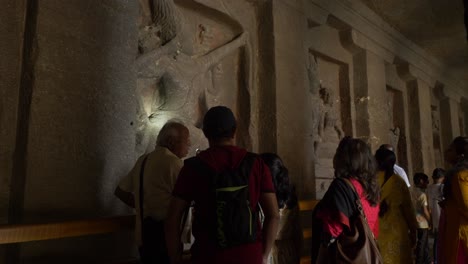 Una-Guía-Que-Muestra-Los-Intrincados-Detalles-De-Las-Estatuas-Talladas-A-Los-Turistas-Indios-Dentro-De-Las-Cuevas-Hindúes-Y-Budistas-De-Ellora