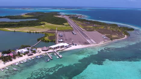 Aerial-view-of-fishing-village-with-small-airport,-airplanes-and-runway,-dolly-out