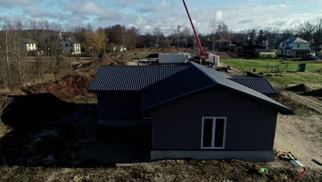 Drone-Aéreo-Girando-Sobre-Una-Casa-Recién-Construida-Con-Paredes-De-Madera-Negra-En-Un-Municipio-Recientemente-Desarrollado-En-Un-Día-Soleado