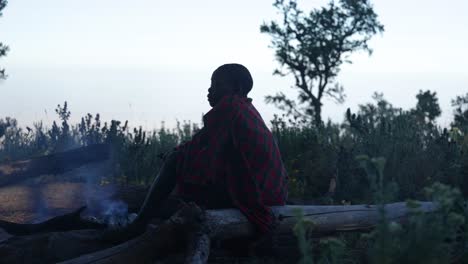 A-young-African-boy-in-a-traditional-tribal-blanket-sits-down-among-nature