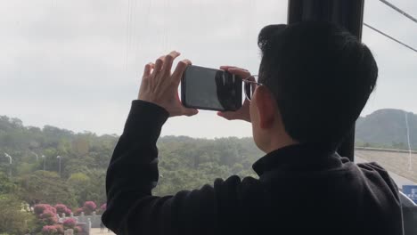 Tourist-takes-picture-of-the-Big-Buddha-from-the-Ngong-Ping-cable-car-with-the-Big-Buddha-in-the-background