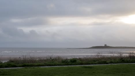 Time-lapse-overlooking-Skerries-Beach-with-the-Martello-Tower-on-Shenick-Island-in-the-distance-as-grey-rainclouds-pass-by,-Ireland