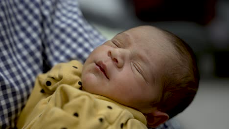 Newborn-Indian-baby-boy-sleeping-peacefully-in-a-yellow-outfit-with-polka-dots,-close-up