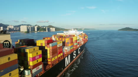 Eine-Nahaufnahme-Eines-Großen-MSC-Containerschiffs,-Das-Hongkong-Verlässt,-Mit-Einer-Drohne-Rückwärts