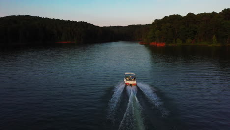 Seguimiento-Hacia-Delante-De-Un-Pequeño-Barco-A-Motor-Conduciendo-Sobre-La-Superficie-Del-Lago-Al-Atardecer