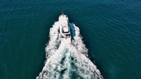 Speedboat-with-tourists-on-board-navigating-over-blue-sea-water-leaving-long-white-wake-trail