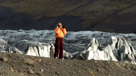 Mujer-Turista-Con-Chaqueta-Amarilla-Con-El-Glaciar-Svinafell-Al-Fondo-En-Islandia