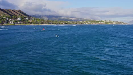 royal-blue-ocean-water-is-dotted-with-kite-boarders-as-this-drone-footage-shows-the-volcanic-formation-of-Diamond-Head-on-the-island-of-Oahu-Hawaiian-islands