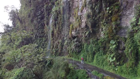 La-Antena-Sigue-A-Un-Ciclista-Donde-Una-Cascada-Cae-Sobre-Yungas-Rd,-Bolivia.