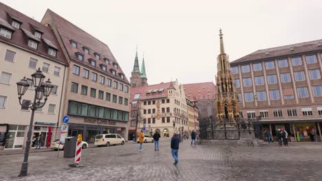 Tourists-visiting-the-beautiful-fountain-in-the-central-market-of-Nuremberg,-Germany-after-a-light-snowfall