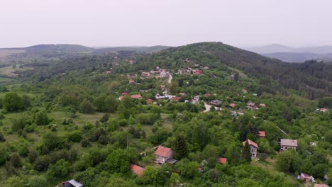 Approaching-drone-shot-moving-above-the-neighborhood-of-Tsarichina-Hole-Village,-showing-the-hills-and-mountains-surrounding-it-in-a-countryside-in-Bulgaria