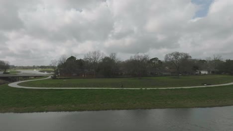 Una-Toma-Aérea-De-Seguimiento-Muestra-A-Un-Ciclista-Cabalgando-Por-Exploration-Green-En-Un-Día-Oscuro-Y-Nublado-En-Clear-Lake,-Houston,-Texas.