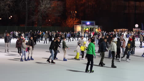 Gente-Disfrutando-De-La-Noche-Patinando-Sobre-Hielo-En-La-Pista-De-Hielo-Del-Parque-De-La-Ciudad-De-Budapest,-Hungría