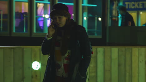 Girl-phoning-on-ice-skates-and-having-a-talk-while-skating-at-night