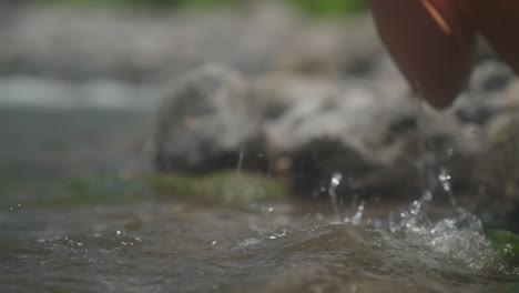 Female-hands-scooping-fresh-water-from-creek,-close-up