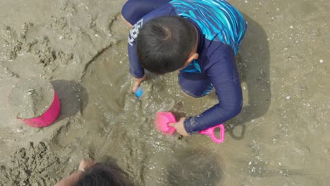 Dos-Niños-Asiáticos-Jugando-En-La-Arena-De-Una-Hermosa-Playa