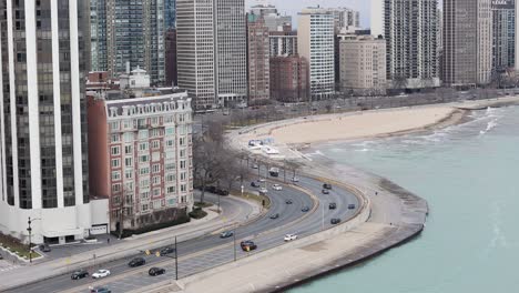 Aerial-of-Oak-Street-Beach-with-Lakefront-Road-Traffic,-Chicago