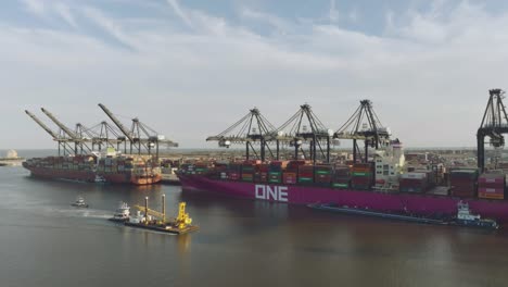 An-aerial-view-of-a-tugboat-moving-a-crane-mounted-barge-into-the-Port-of-Houston's-Bayport-Container-Terminal-in-Houston,-Texas