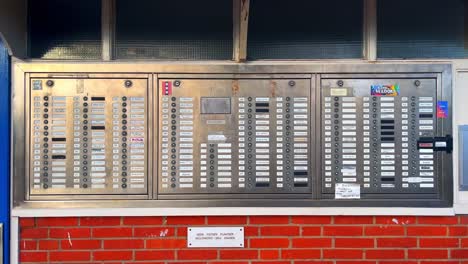 Huge-row-of-doorbells-in-silver-panel-with-nameplates-and-stickers