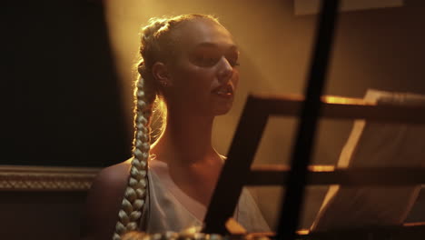 Blonde-hair-Rapunzel-wearing-white-dress-playing-piano-sitting-against-the-sunlight-falling-on-her